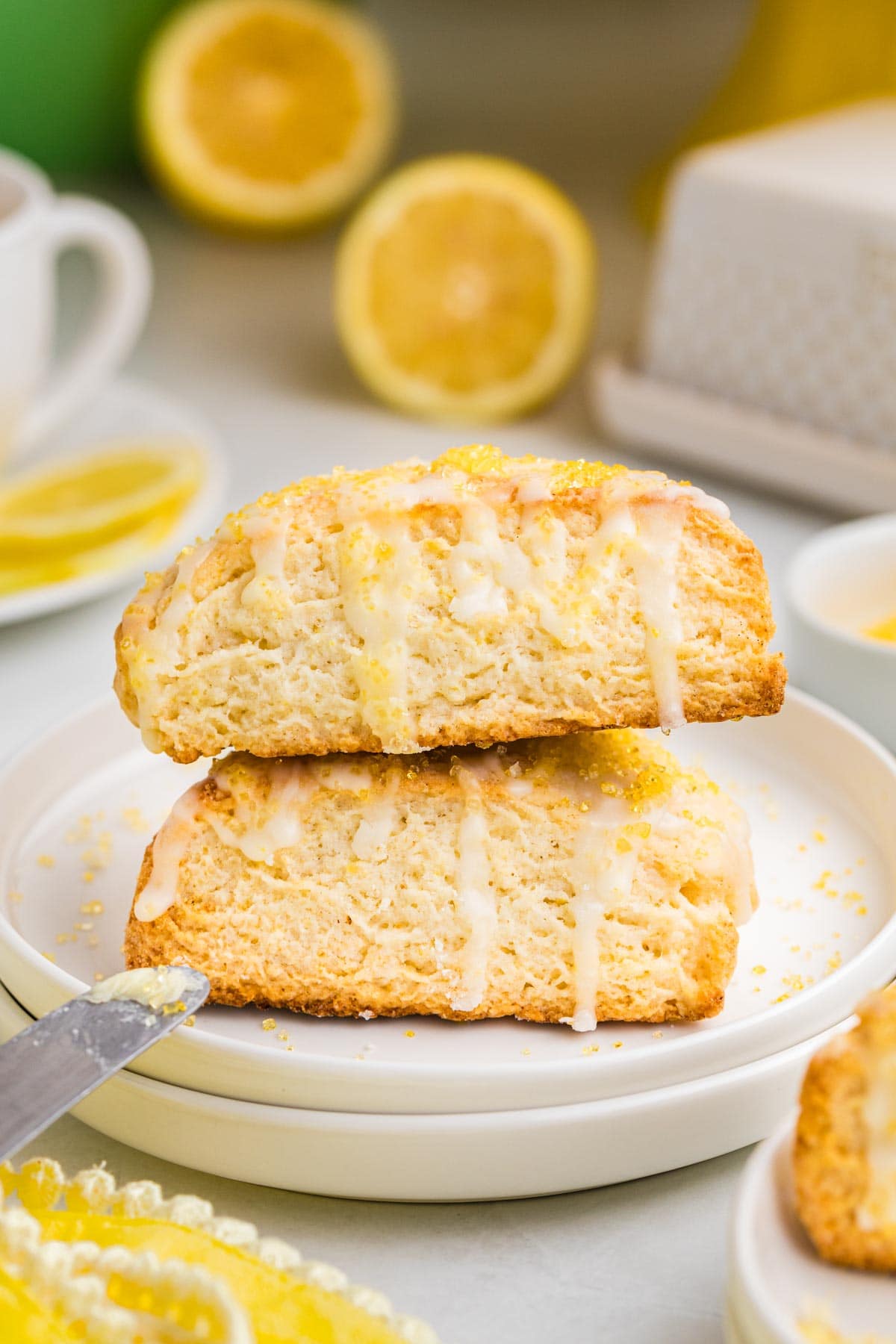 Two lemon cream scones drizzled with glaze stacked on top of each other.