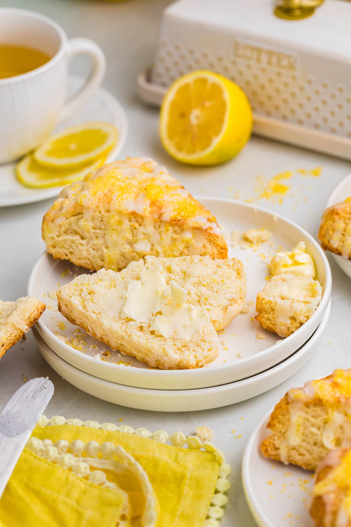 Lemon cream scones on a plate with one scone sliced open with butter on it.