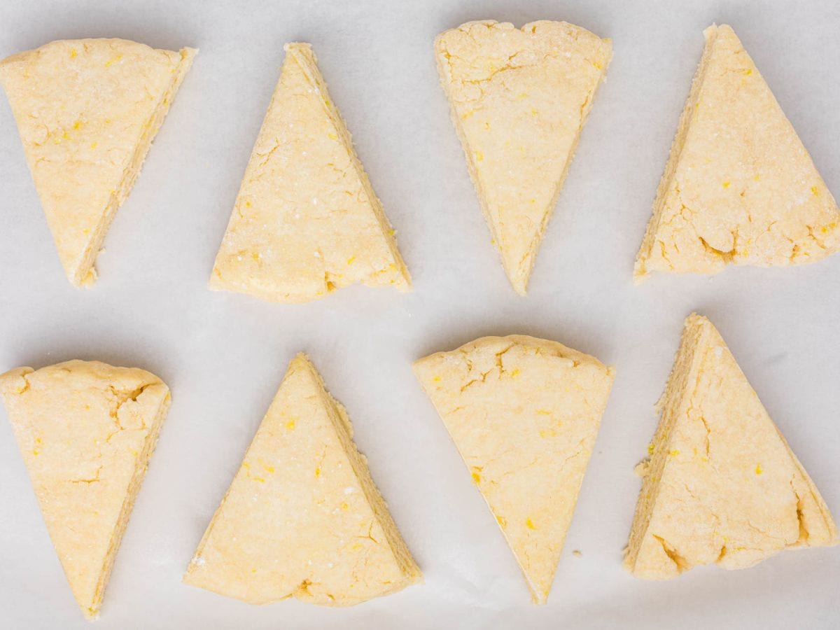 Scone dough cut into triangles and placed on a sheet pan lined with parchment.