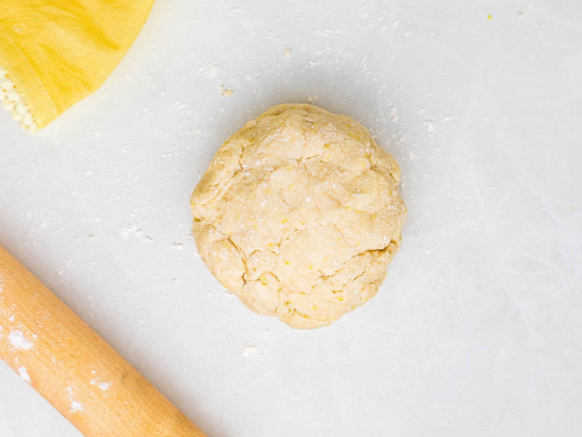 Scone dough in a disc on a floured surface next to a rolling pin.