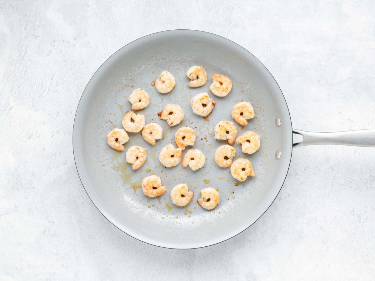 A skillet with shrimp being sautéed.