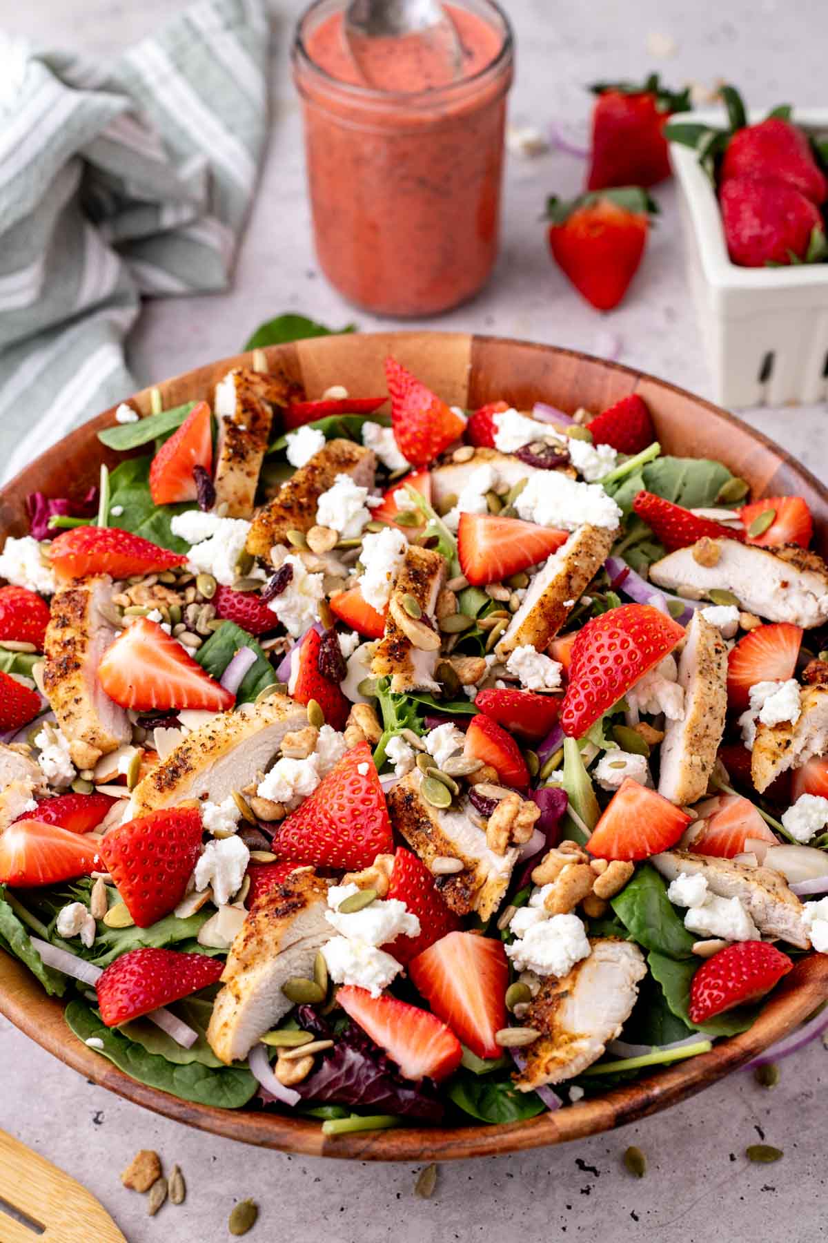 Strawberry salad with chicken served in a large wooden salad bowl.