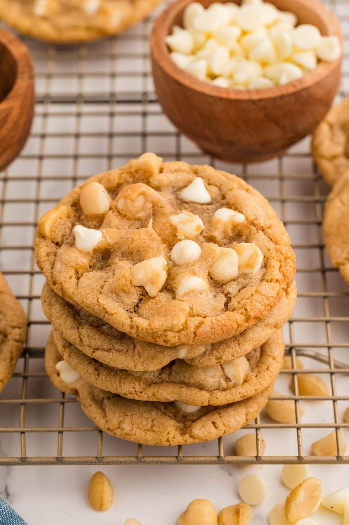 White chocolate macadamia nut cookies stacked on top of each other on a cooling rack.