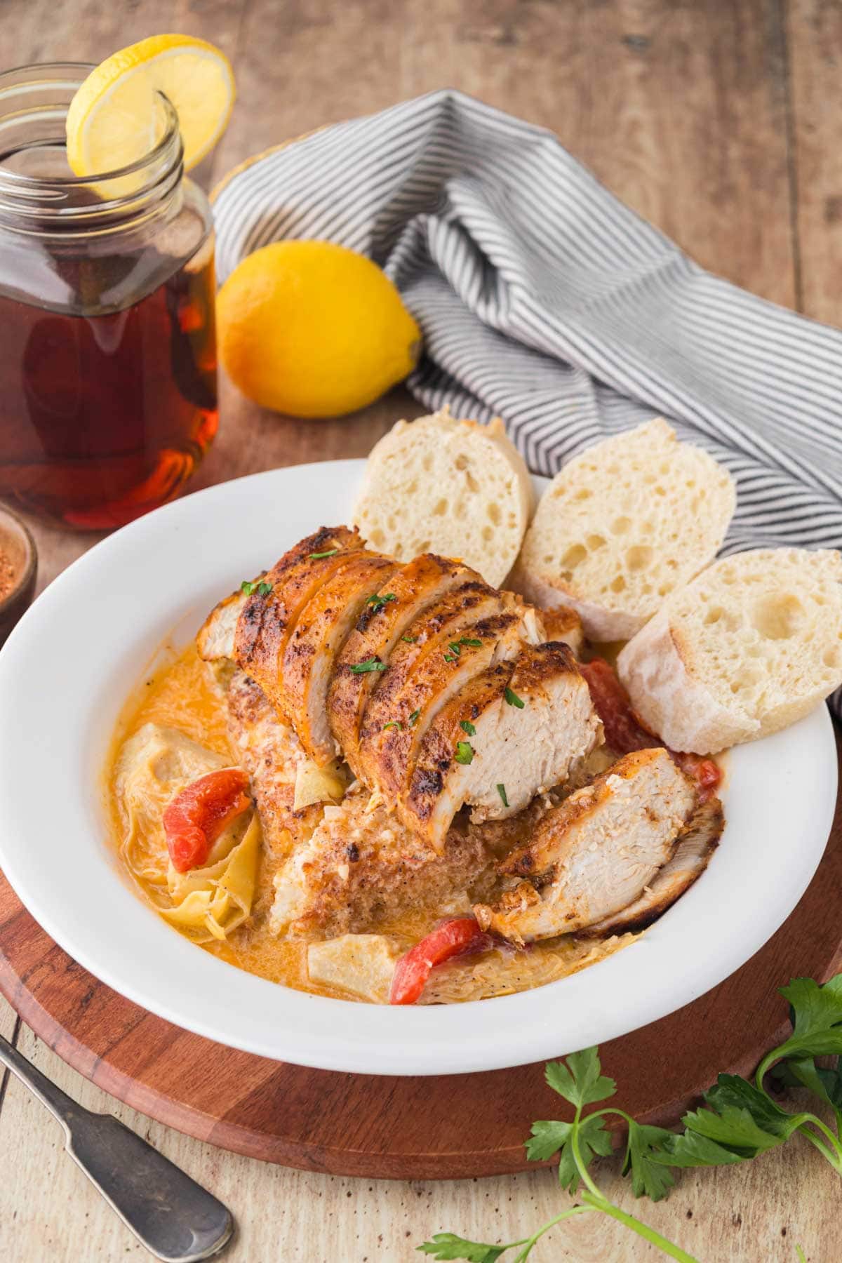 A white bowl with a grit cake on the bottom topped with a lemon butter, cream sauce, and blackened sliced chicken.