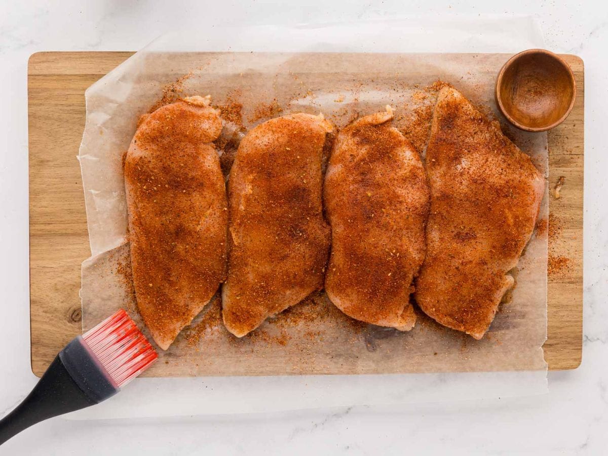 Seasoning all over chicken breast.