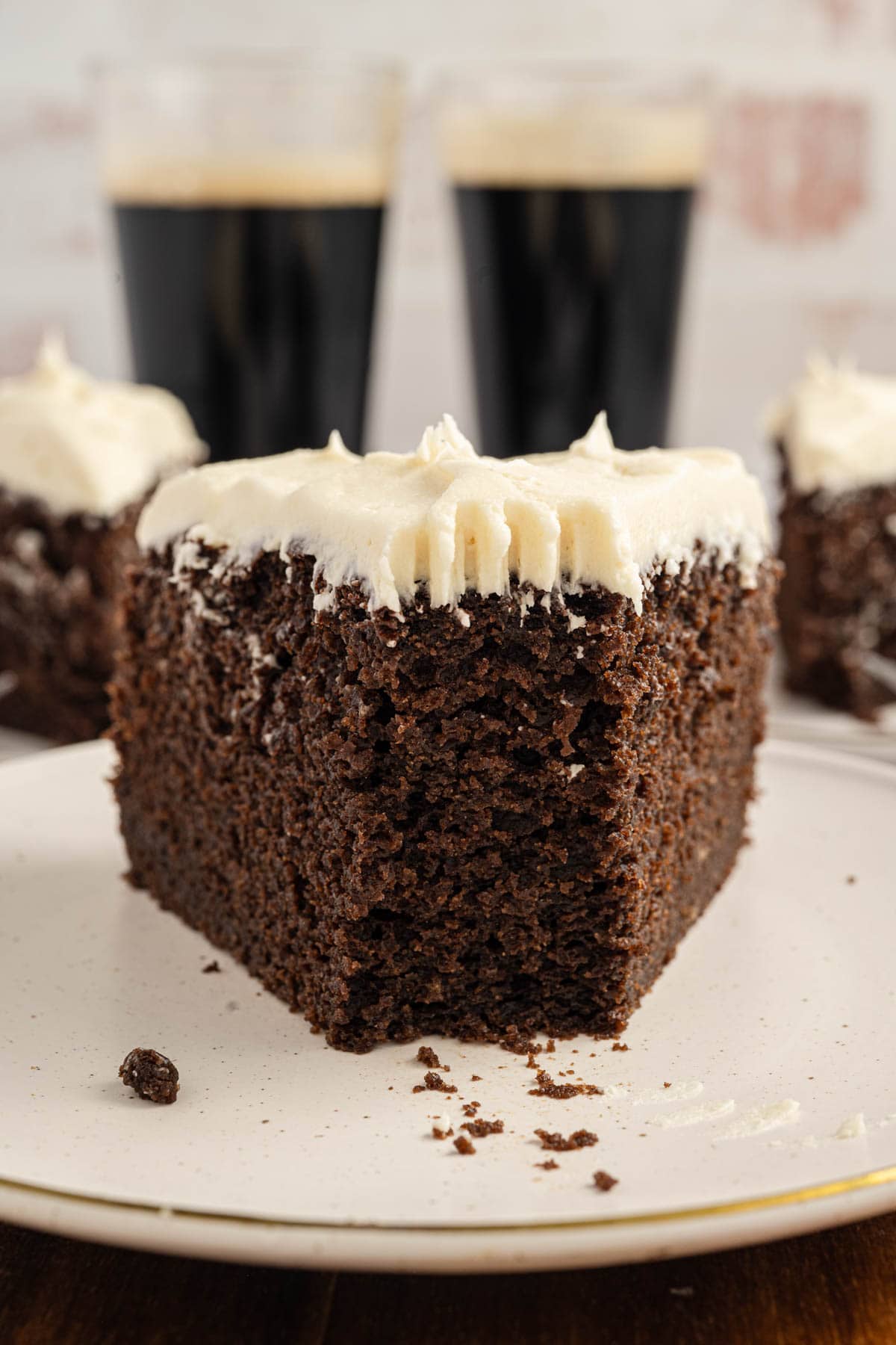 Slice of chocolate stout cake on a plate with a bite missing.