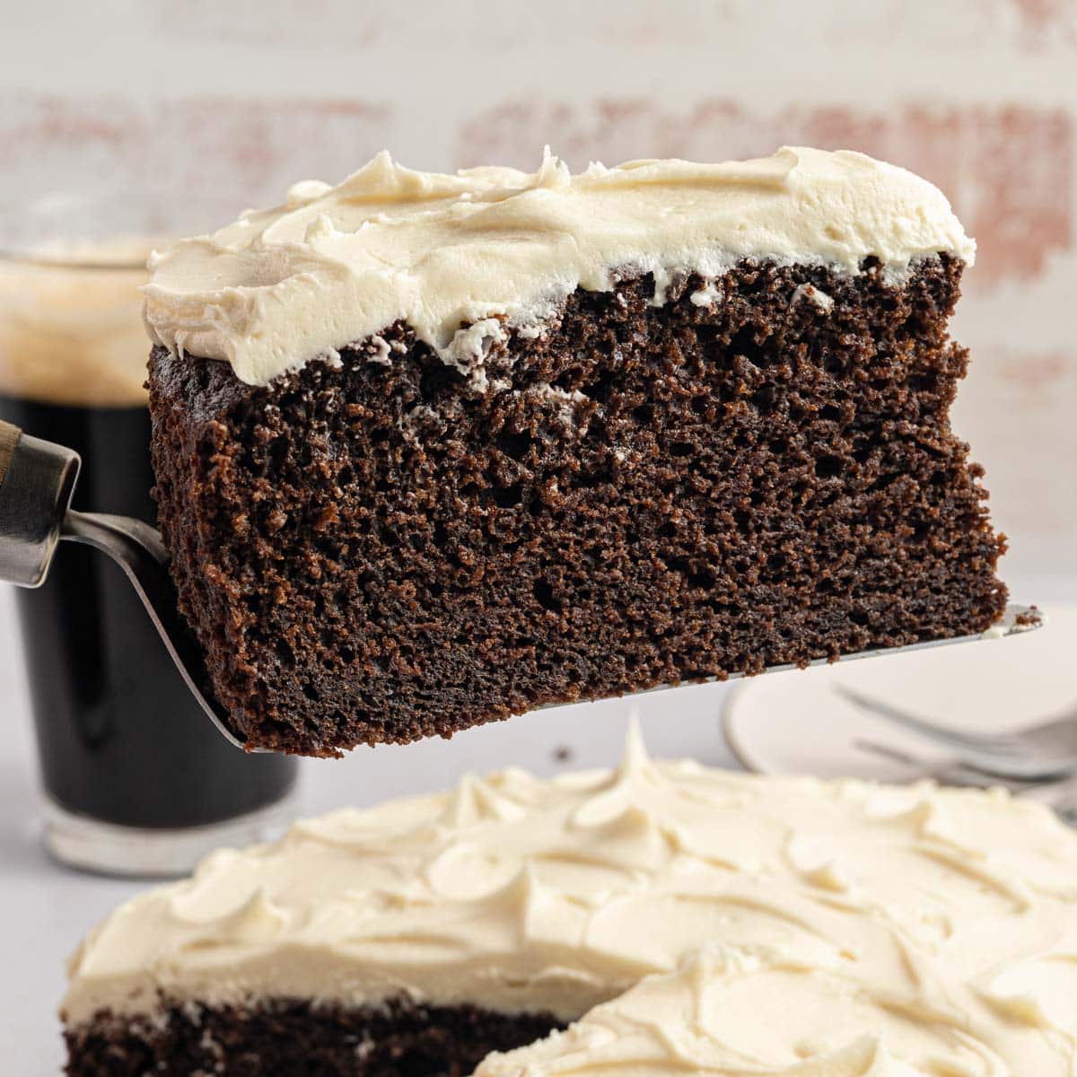 Side view of a spatula holding a slice of chocolate stout cake above the rest of the cake.