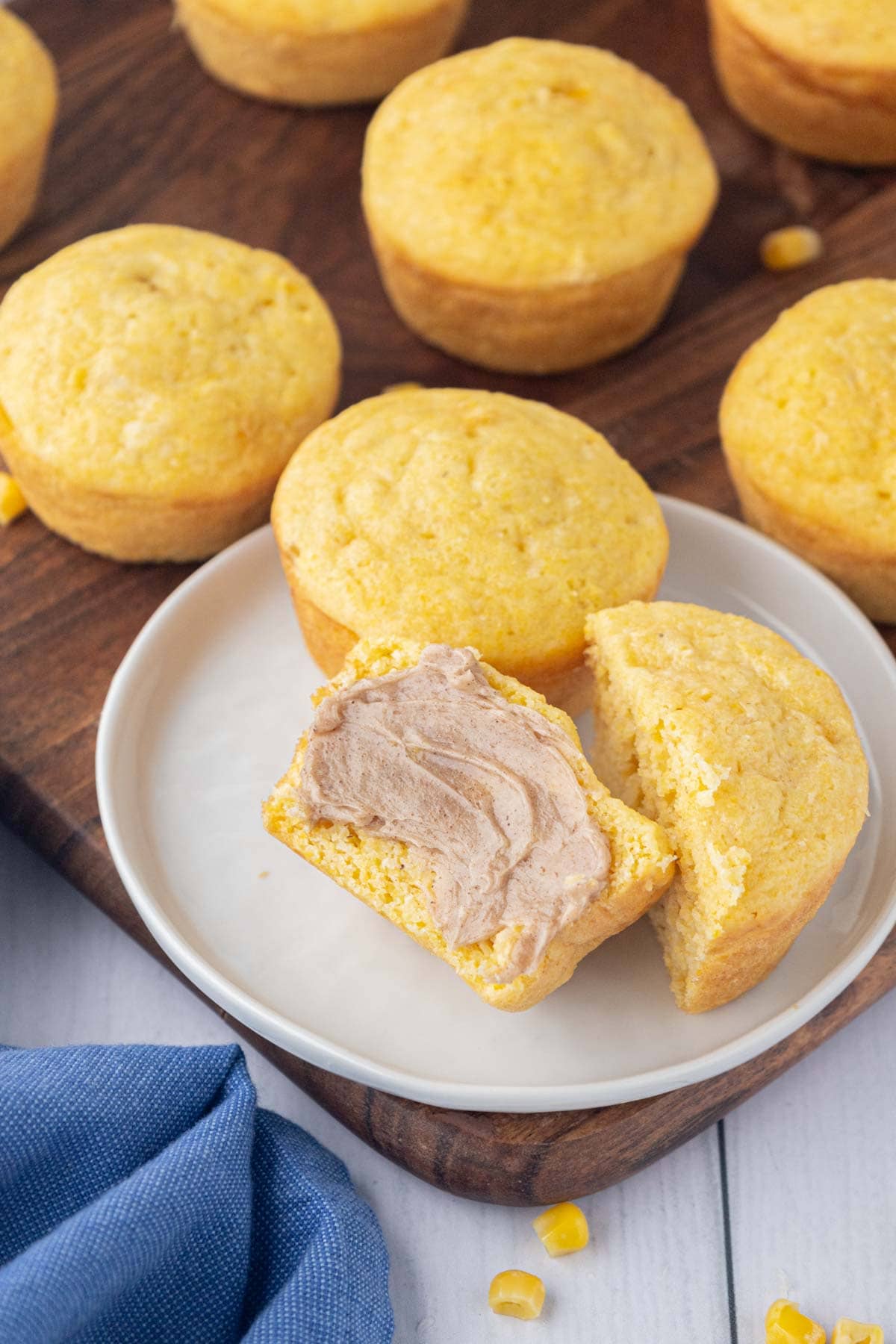 Cornbread muffin on a white plate, sliced in half and slathered with honey cinnamon butter.