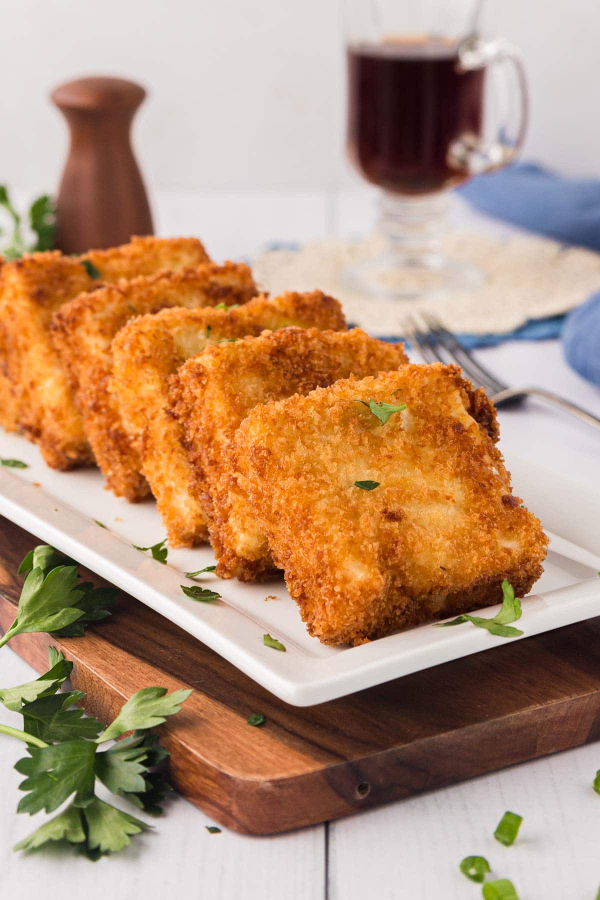 Fried grit cakes on a white serving plate.