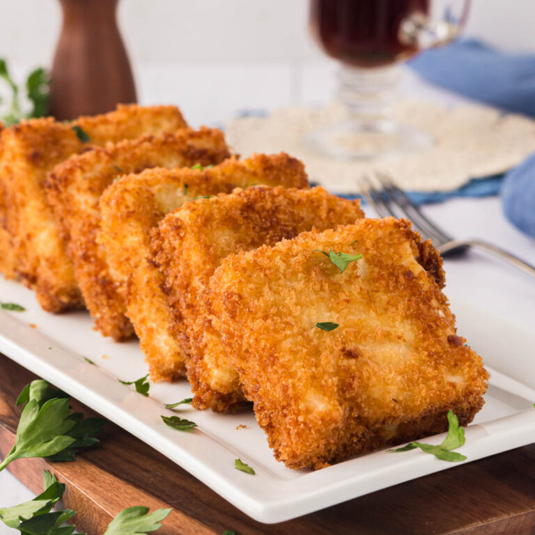 Fried grit cakes on a white serving plate.