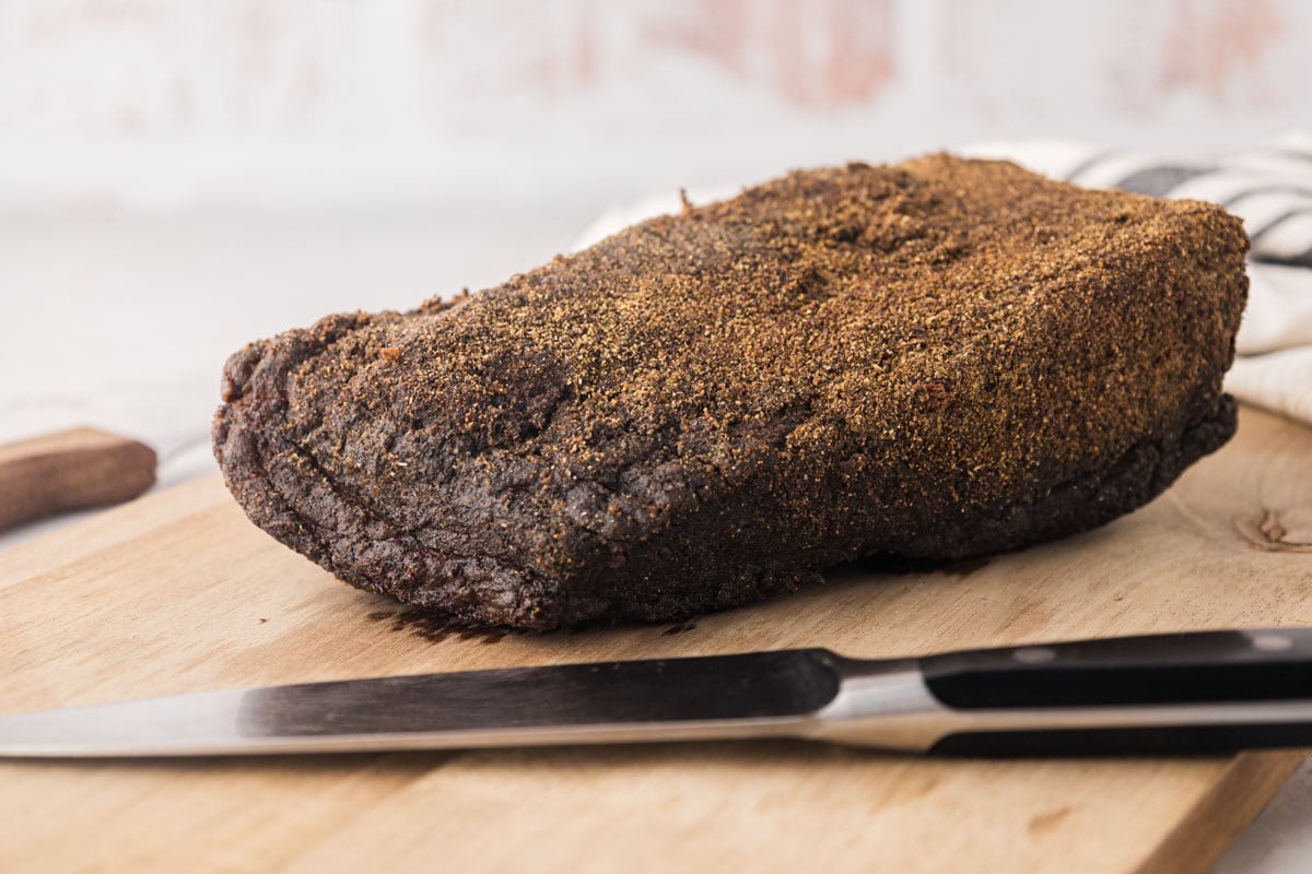 Cooked pastrami on a cutting board.