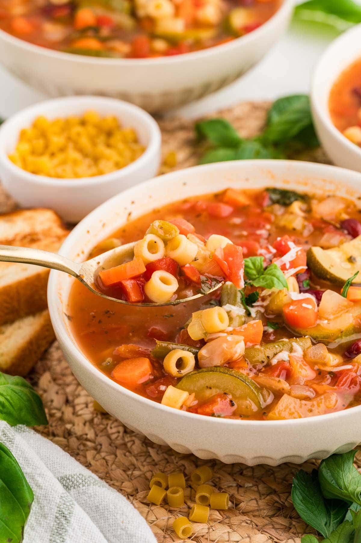 Bowl of minestrone soup with a spoon picking up a bite.