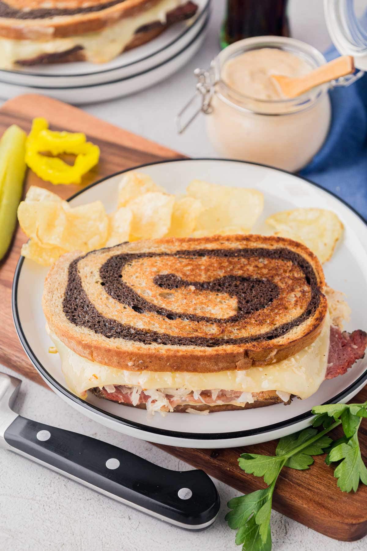 A Reuben sandwich with the Russian dressing container in the background.