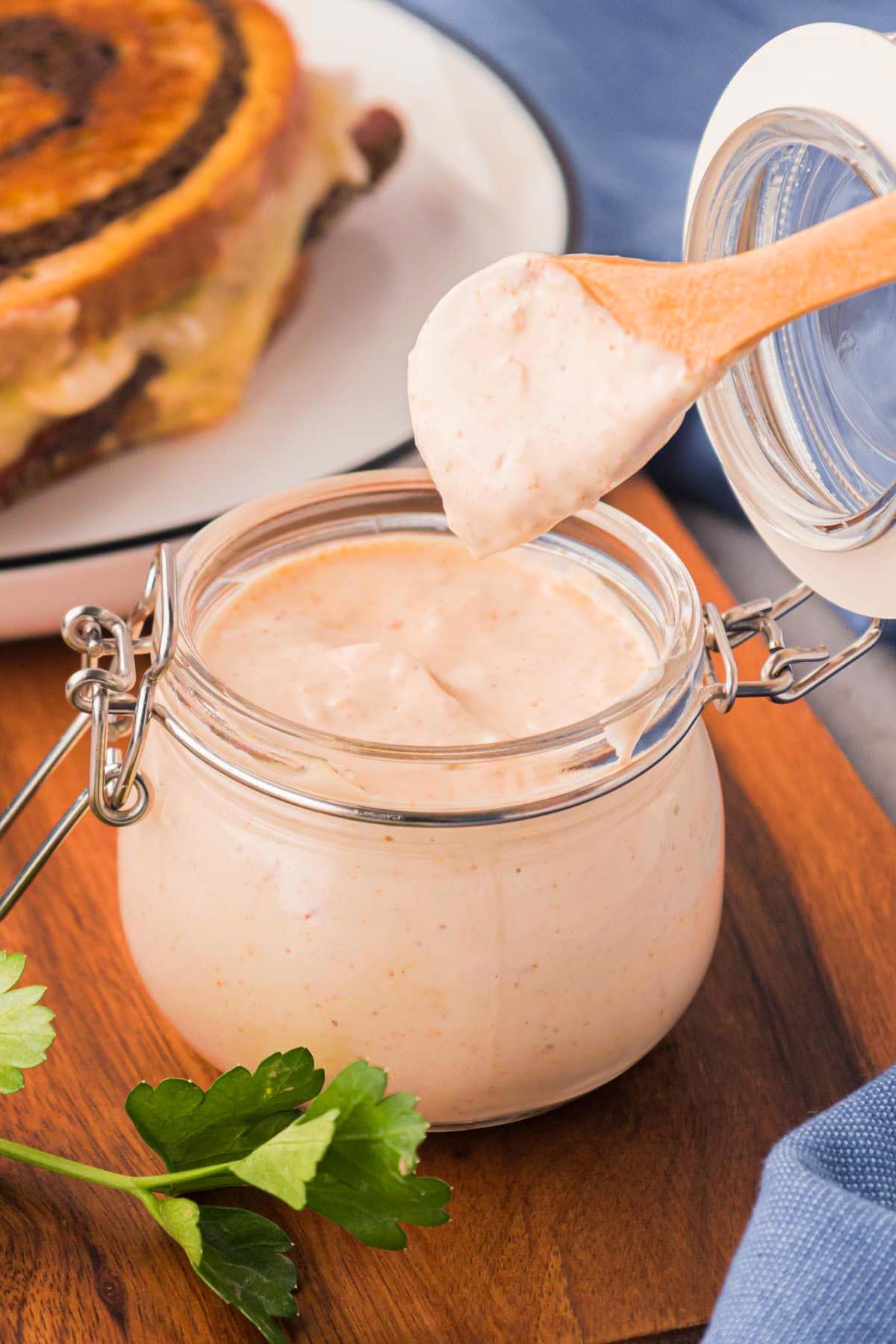 A jar with a spoon, taking some dressing out out of it.