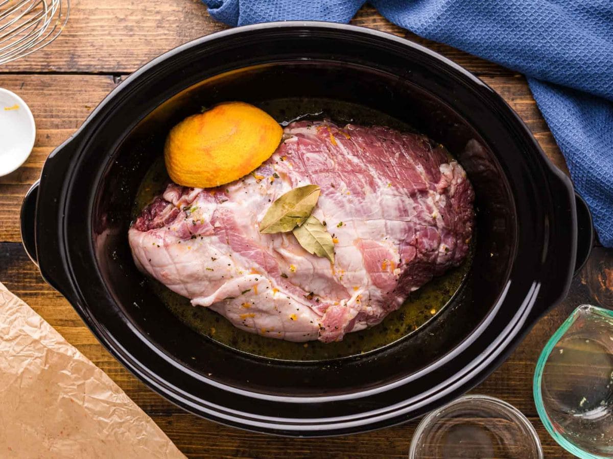 Bay leaves and orange added to slow cooker.