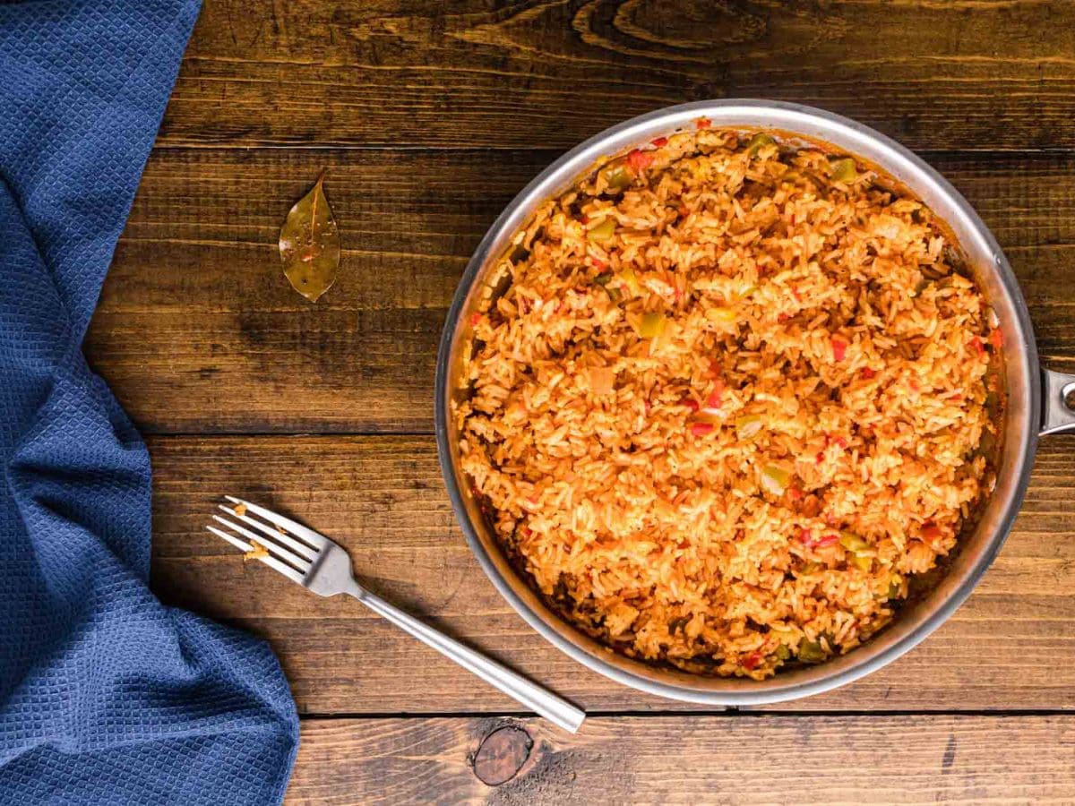 The skillet of fluffed Arroz Amarillo rice with the bay leaf removed