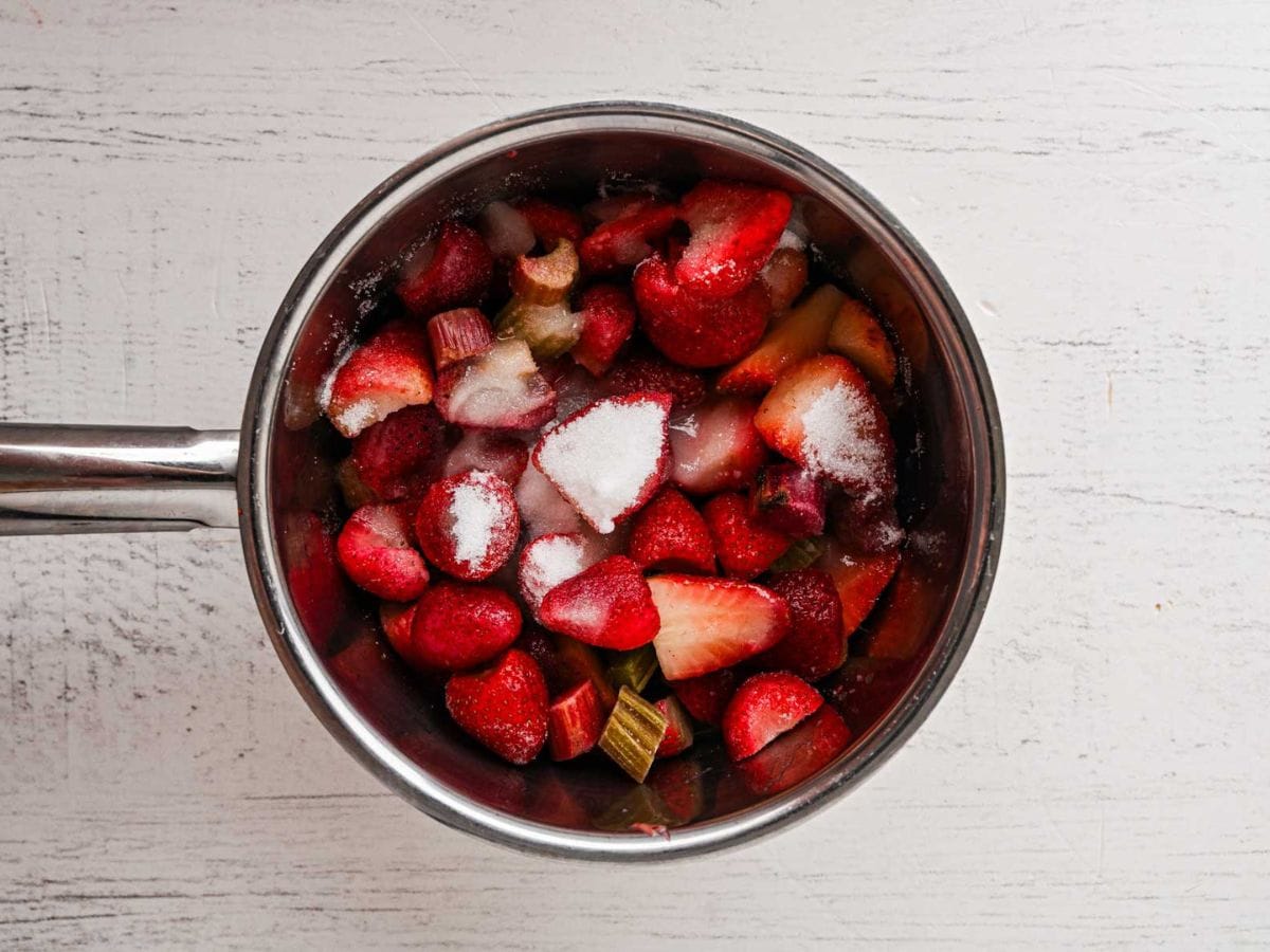 Strawberries, rhubarb, sugar and lemon in a saucepan.