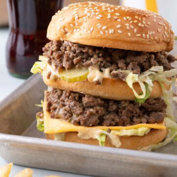 Side view of a big mac sloppy joe with lots of layers, served on a sheet pan.