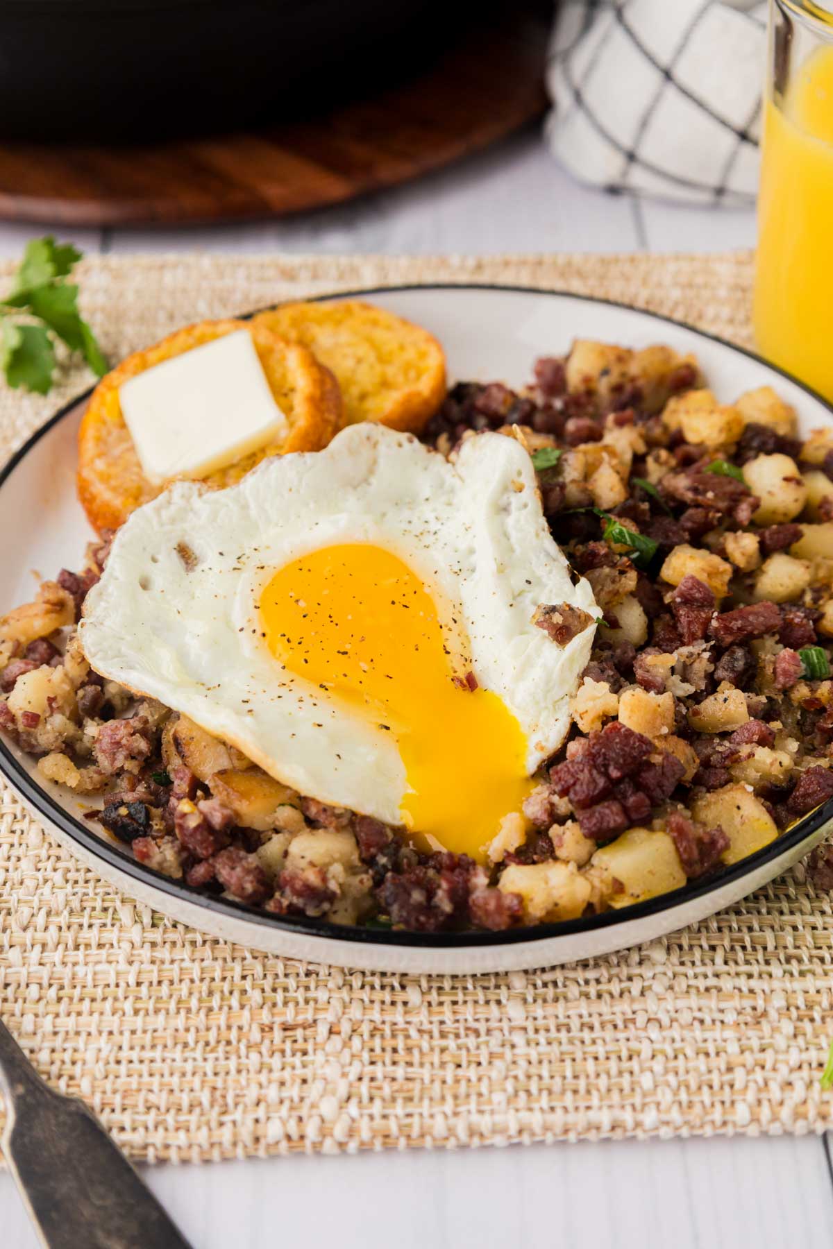 Fried egg on top of a bed of corned beef hash on a plate.