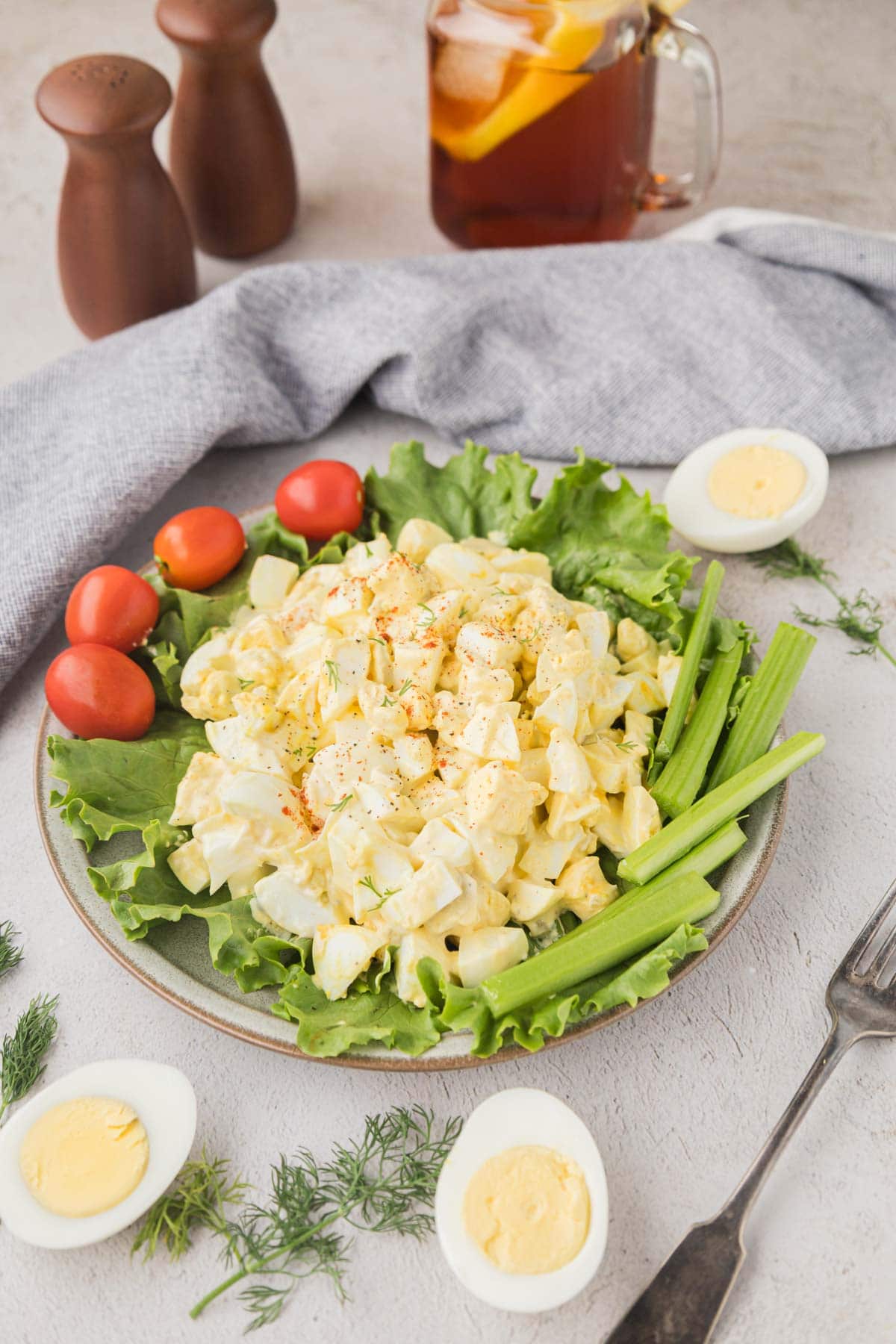 Egg salad set on a bed of lettuce with cherry tomatoes, and celery for garnish.