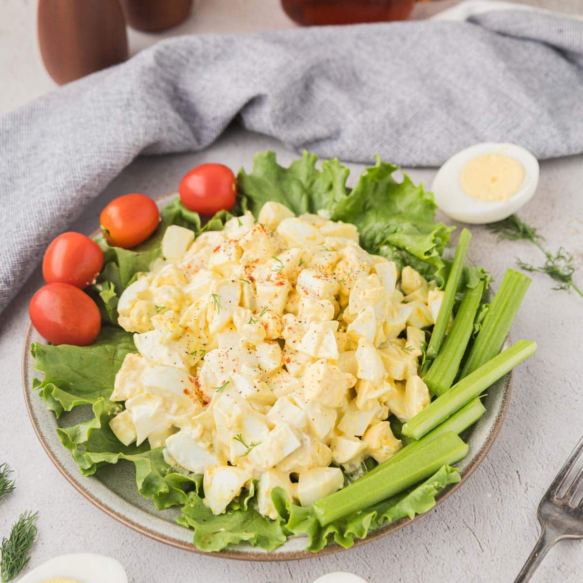 Egg salad set on a bed of lettuce with cherry tomatoes, and celery for garnish