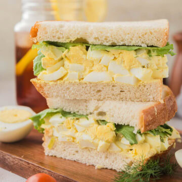 Egg salad sandwich on a wooden serving tray.