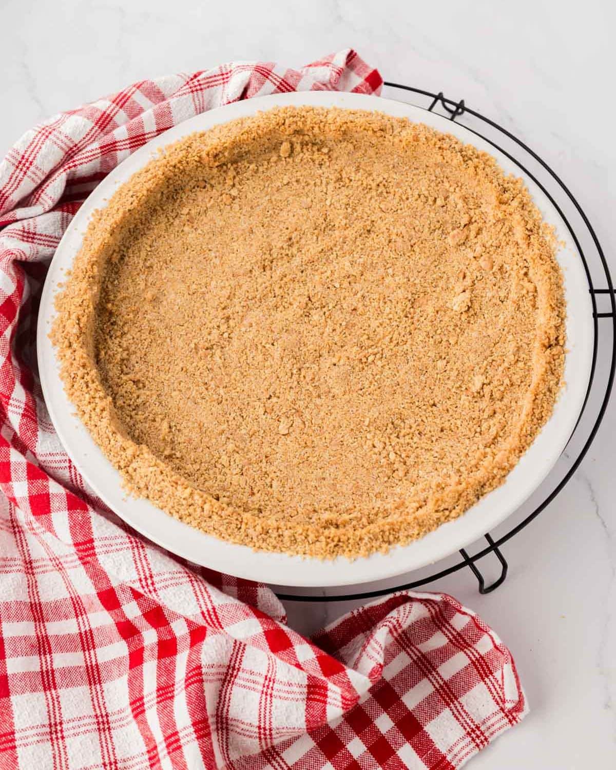 A baked graham cracker pie crust on a cooling rack.