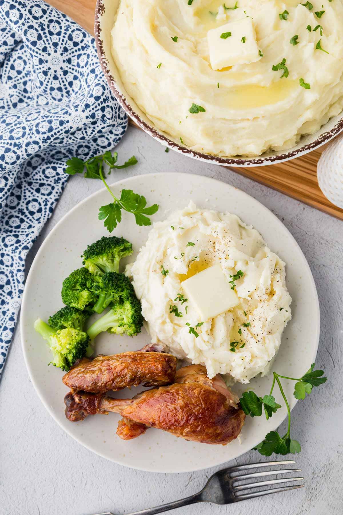 Overhead shot of mashed potatoes served with broccoli and chicken on a plate.