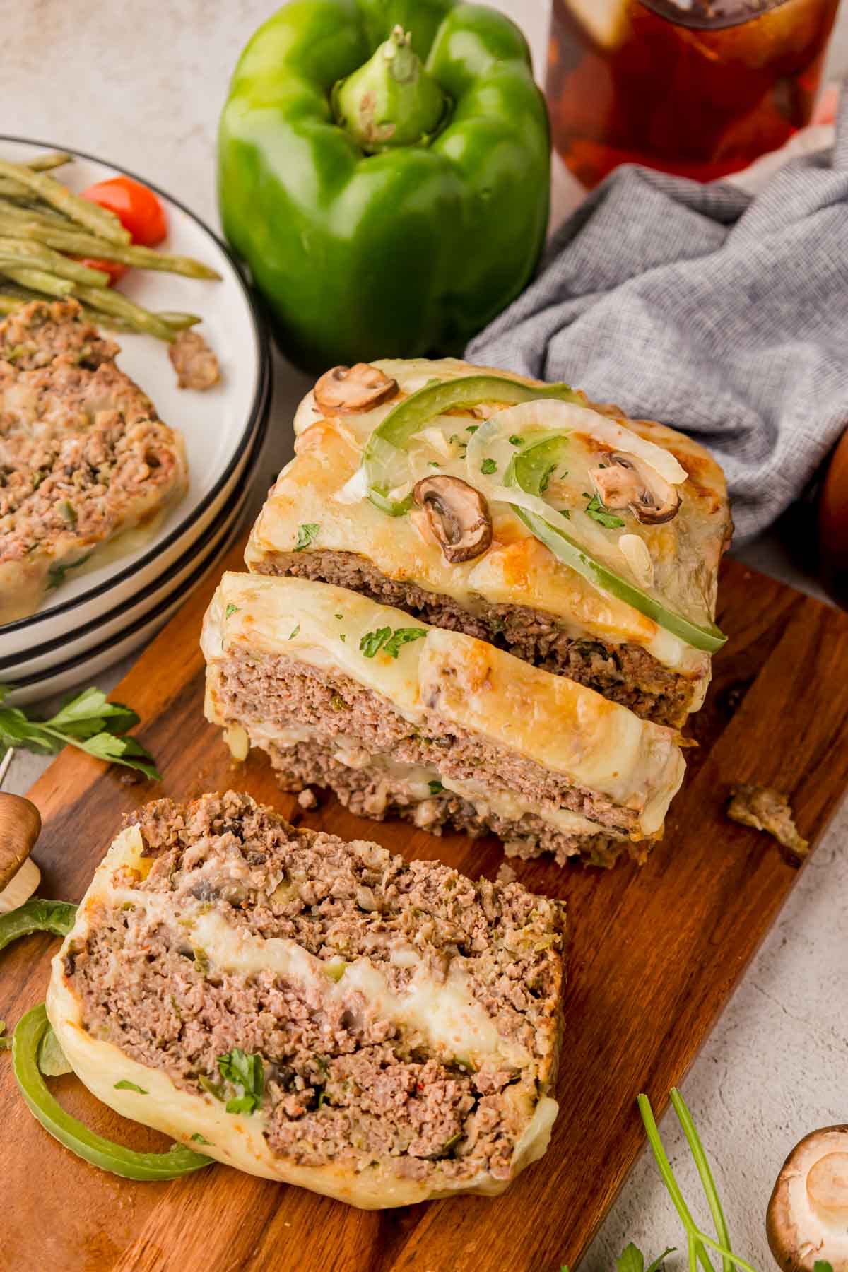 Philly cheesesteak meatloaf on a wooden board with some slices off the end.