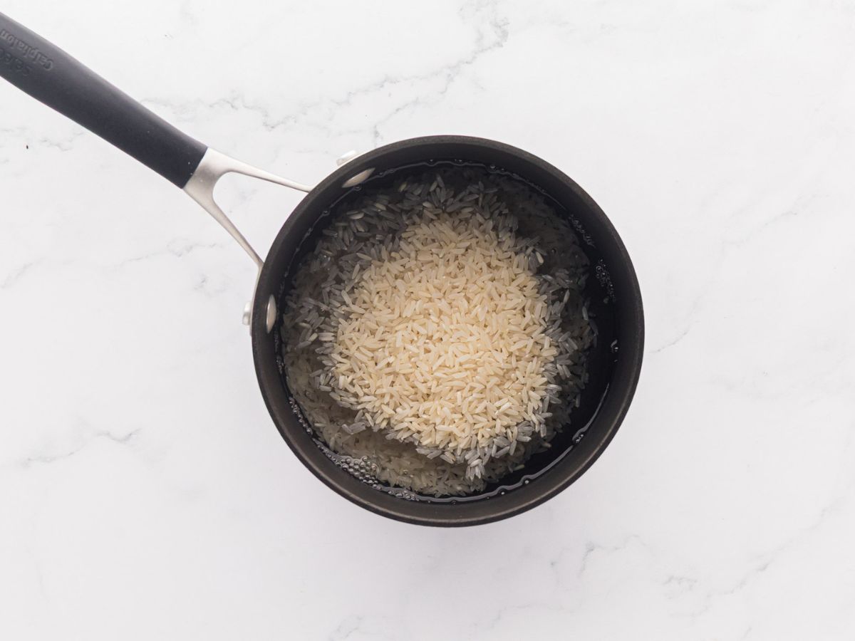 Rice being cooked in a sauce pan.