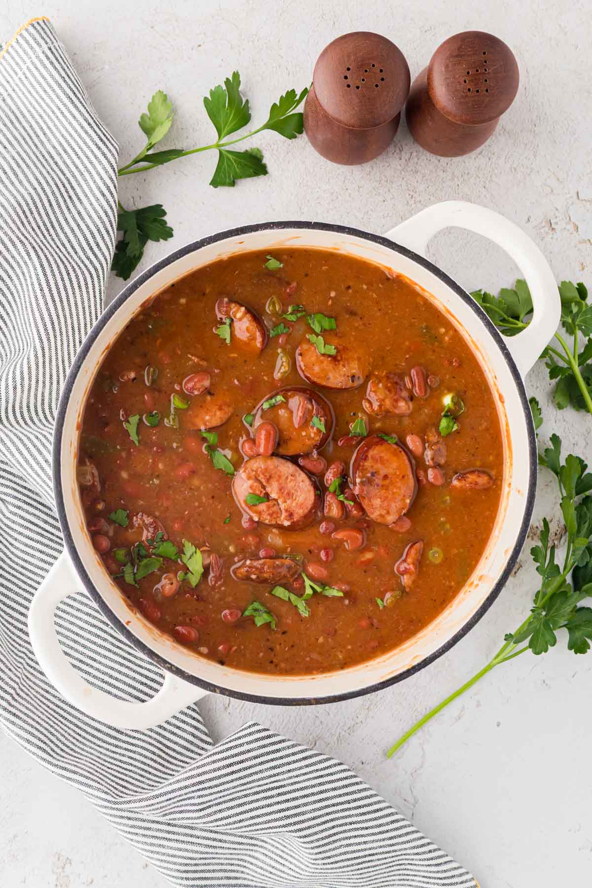 A Dutch oven with red beans and rice cooked with sausage.