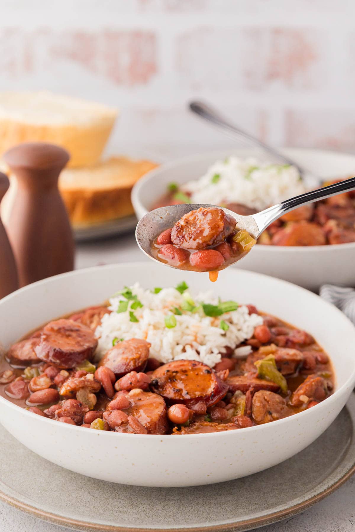 A spoon taking a bite of sausage with red beans.