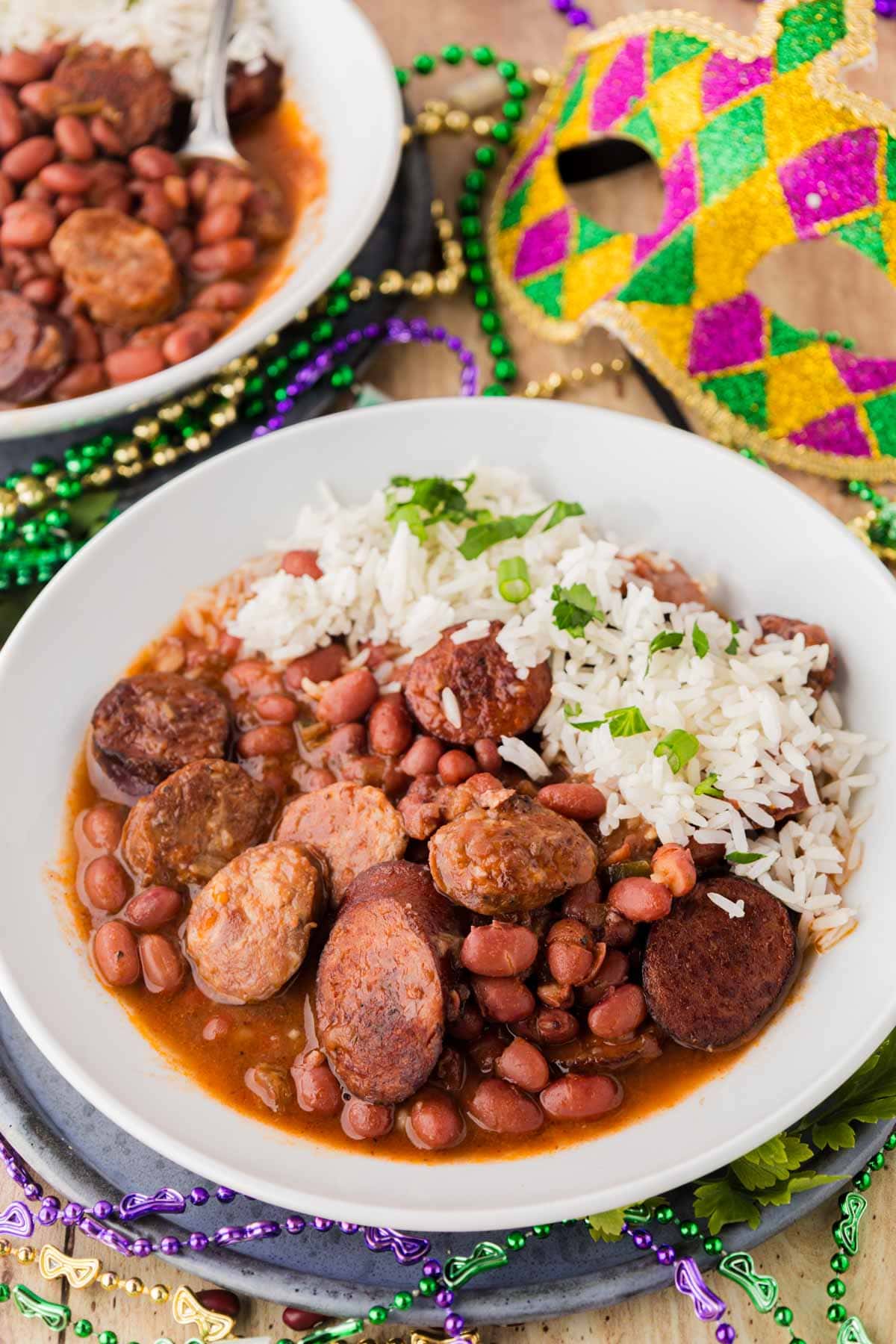 Red beans and rice in a bowl with Mardi Gras decor in the background.