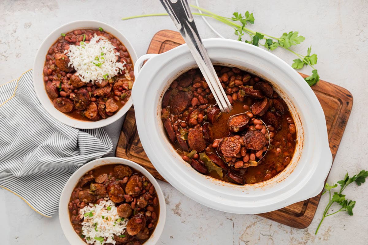 A crockpot filled with red beans and rice and a ladle removing a serving.